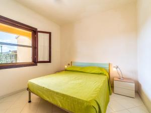 1 dormitorio con 1 cama con colcha verde y ventana en Apartment Ambra - TEO113 by Interhome, en San Teodoro