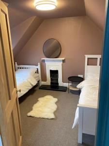 a room with two beds and a mirror and a fireplace at Frasers Apartment in Golspie