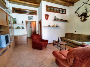 ein Wohnzimmer mit einem Sofa, Stühlen und einem TV in der Unterkunft Apartment Il Castello-2 by Interhome in Albonico