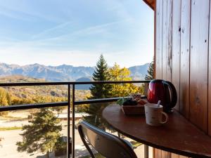 a table and chairs on a balcony with a view of mountains at Studio Ariane-5 by Interhome in Le Corbier