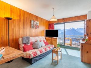 ein Wohnzimmer mit Couch und großem Fenster in der Unterkunft Apartment L'Edioule by Interhome in La Toussuire