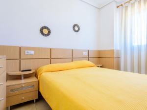 1 dormitorio con 1 cama amarilla y 2 relojes en la pared en Apartment Frente Mar by Interhome, en Oropesa del Mar