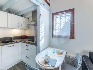 a small white kitchen with a table and a window at Holiday Home lotissement Les Rives de Capbreton by Interhome in Capbreton