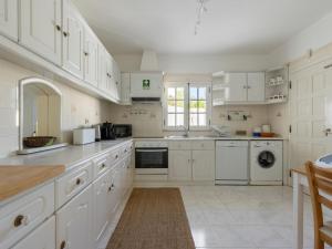 ヴィラモウラにあるVilla Villa Verde by Interhomeの白いキャビネットと電化製品付きの広い白いキッチン