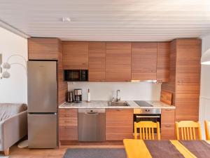 a kitchen with wooden cabinets and a stainless steel refrigerator at Holiday Home Kätkäläinen e 2 by Interhome in Sirkka