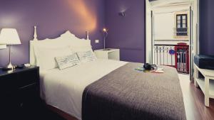 a bedroom with a large bed with purple walls at Bartholomeu Guesthouse in São Bartolomeu de Messines