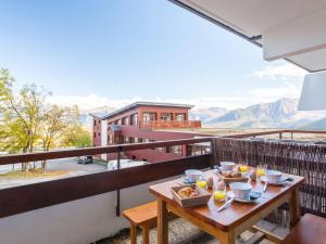 a table with food on a balcony with mountains at Apartment Pegase Phenix-70 by Interhome in Le Corbier