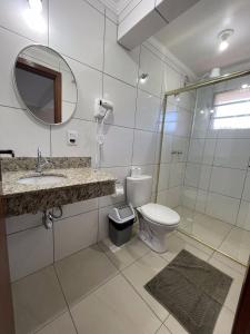 a bathroom with a toilet and a sink and a mirror at Vila Betânia in Porto Alegre