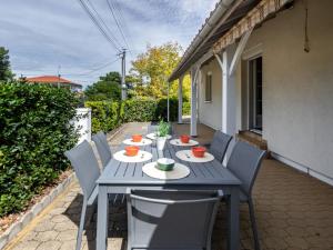 a wooden table with chairs on a patio at Holiday Home Pyrénées by Interhome in Capbreton