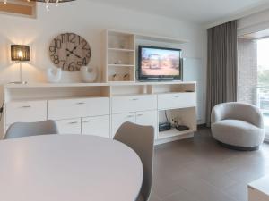 een woonkamer met een tv en een tafel en stoelen bij Apartment Sea Breeze by Interhome in Bredene
