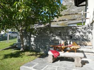 a picnic table in a yard next to a stone wall at Holiday Home Casa Al Noce by Interhome in Olivone