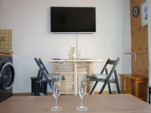 due bicchieri da vino seduti su un tavolo con televisore di Apartment Pointe des Aravis-5 by Interhome a Saint-Gervais-les-Bains