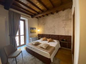 a bedroom with a bed and a chair and a window at Condotti Rooms in Rome