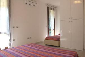 a white bedroom with a bed and a window at Volturnus a soli 150m dal mare con WI FI in Marina di Castagneto Carducci