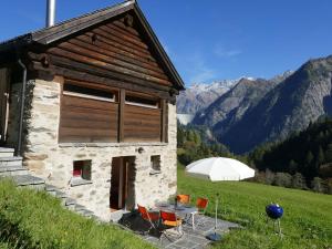 a building with a table and chairs in a field at Holiday Home Rustico Enrico by Interhome in Campo Blenio