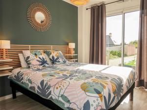 een slaapkamer met een bed met een kleurrijk dekbed en een raam bij Holiday Home Villa Ty Coz by Interhome in Cléder