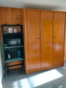 d'une grande armoire en bois avec un four micro-ondes. dans l'établissement Appartement situé en plein centre à deux pas des pistes., à Besse-et-Saint-Anastaise