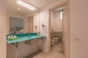 bagno con lavandino, specchio e servizi igienici di Hotel Flamingo a Santa Margherita di Pula