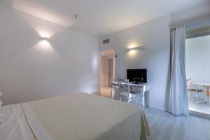 a bedroom with a bed and a desk and a television at Hotel Flamingo in Santa Margherita di Pula