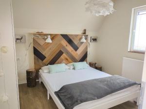a bedroom with a white bed with a wooden wall at Chalet Waldoase by Interhome in Bad Arolsen