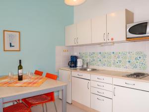 una cocina con armarios blancos y una mesa con una botella de vino en Apartment Elena - SNJ115 by Interhome, en Senj