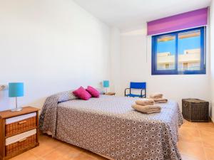 Un dormitorio con una cama con almohadas rosas y una ventana en Apartment Las Dunas by Interhome, en Moncófar