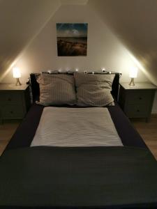 a bedroom with a bed with two nightstands and two lamps at Mansarde Ferienwohnung - Modern - Zentral - PayTV in Wilhelmshaven