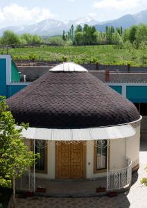 un piccolo edificio con tetto marrone con montagne sullo sfondo di Barskoon Guest House a Barskoon