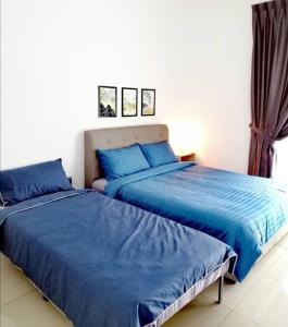 2 camas en un dormitorio con sábanas azules en Desaru Sweet and Cozy Home,11pax, Mini Pool, Beach ,Waterpark, Wifi, BBQ, en Bandar Penawar