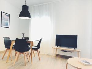 a living room with a table with chairs and a television at Apartamentos La Gloria in Benidorm