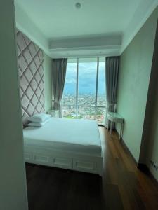 1 dormitorio con cama y ventana grande en City Penthouse with Jakarta Skyline, en Yakarta