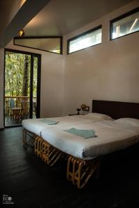 a large bed in a room with windows at Uravu Bamboo Grove Resort in Wayanad