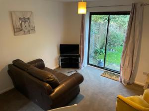 Una sala de estar con un sofá de cuero y un televisor. en Serviced Accommodation 2 bed house III, en Worcester