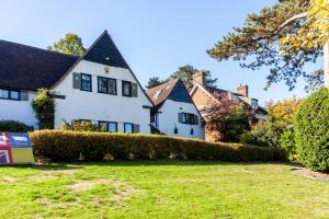 a white house with a hedge in the yard at 83 Downs Hill in Beckenham