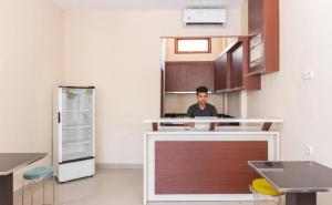 a man sitting at a counter in a kitchen at RedDoorz Syariah @ Batua Raya in Makassar