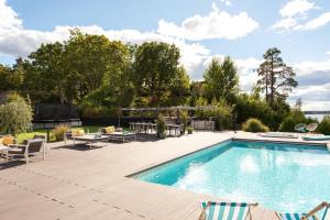 a swimming pool with chairs and a patio with at Exclusive Lakefront Mansion with pools in Stockholm in Tyresö