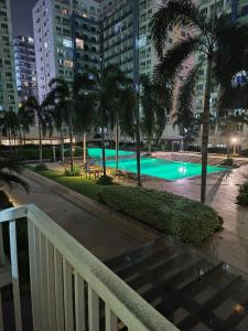 - une piscine avec des palmiers et des bâtiments la nuit dans l'établissement Amigo's Place at Sea Residences, à Manille