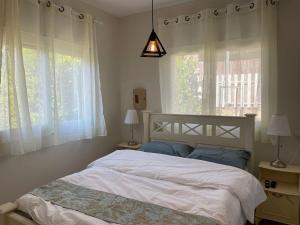 a bedroom with a white bed and a window at Alma BaHar - charming 2 bdrm house with garden עלמה בהר - דירת אירוח בלב גן פורח in Zikhron Ya'akov
