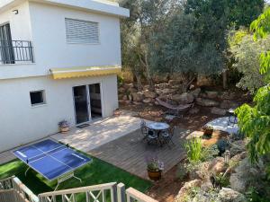 a backyard with a deck and a table and chairs at Alma BaHar - charming 2 bdrm house with garden עלמה בהר - דירת אירוח בלב גן פורח in Zikhron Ya'akov
