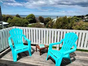 two blue chairs and a table on a deck at Seahaven in Lake Tyers