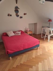um quarto com uma cama vermelha e piso em madeira em Les Géraniums em Baden