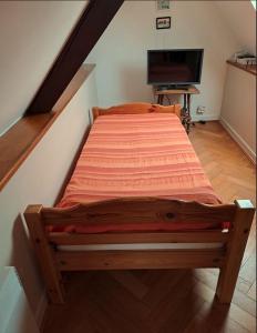 uma cama de madeira num quarto com televisão em Les Géraniums em Baden