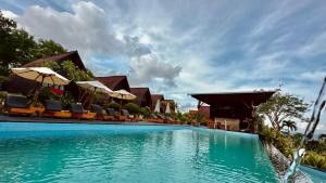 a swimming pool at a resort with chairs and umbrellas at Bataran Garden Cottage in Nusa Penida
