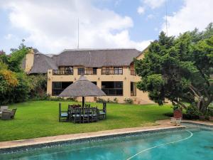 a house with a table and chairs next to a pool at Blue Hills Lodge in Midrand