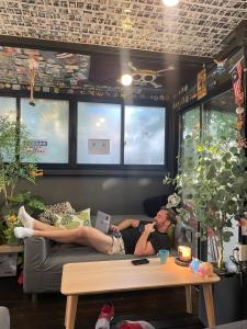 a man laying on a couch in a living room at Zzzip Guesthouse in Hongdae in Seoul