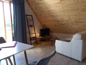 una sala de estar con muebles blancos y techo de madera. en Gîte l'estive du Clozel en Besse-en-Chandesse