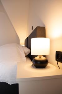 a lamp on a table next to a bed at Hotel Swaenenburg in Oostrozebeke