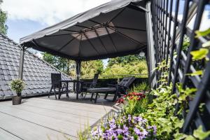 a wooden deck with chairs and an umbrella at Ferienwohnungen Am Heidegarten in Schneverdingen
