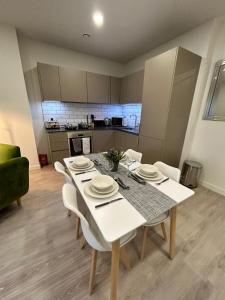 a dining room with a white table and a kitchen at Luxury 1-Bed Town Centre Platform South Stevenage in Stevenage