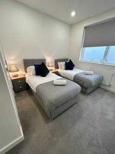 two beds in a room with a window and a couch at Luxury 1-Bed Town Centre Platform South Stevenage in Stevenage